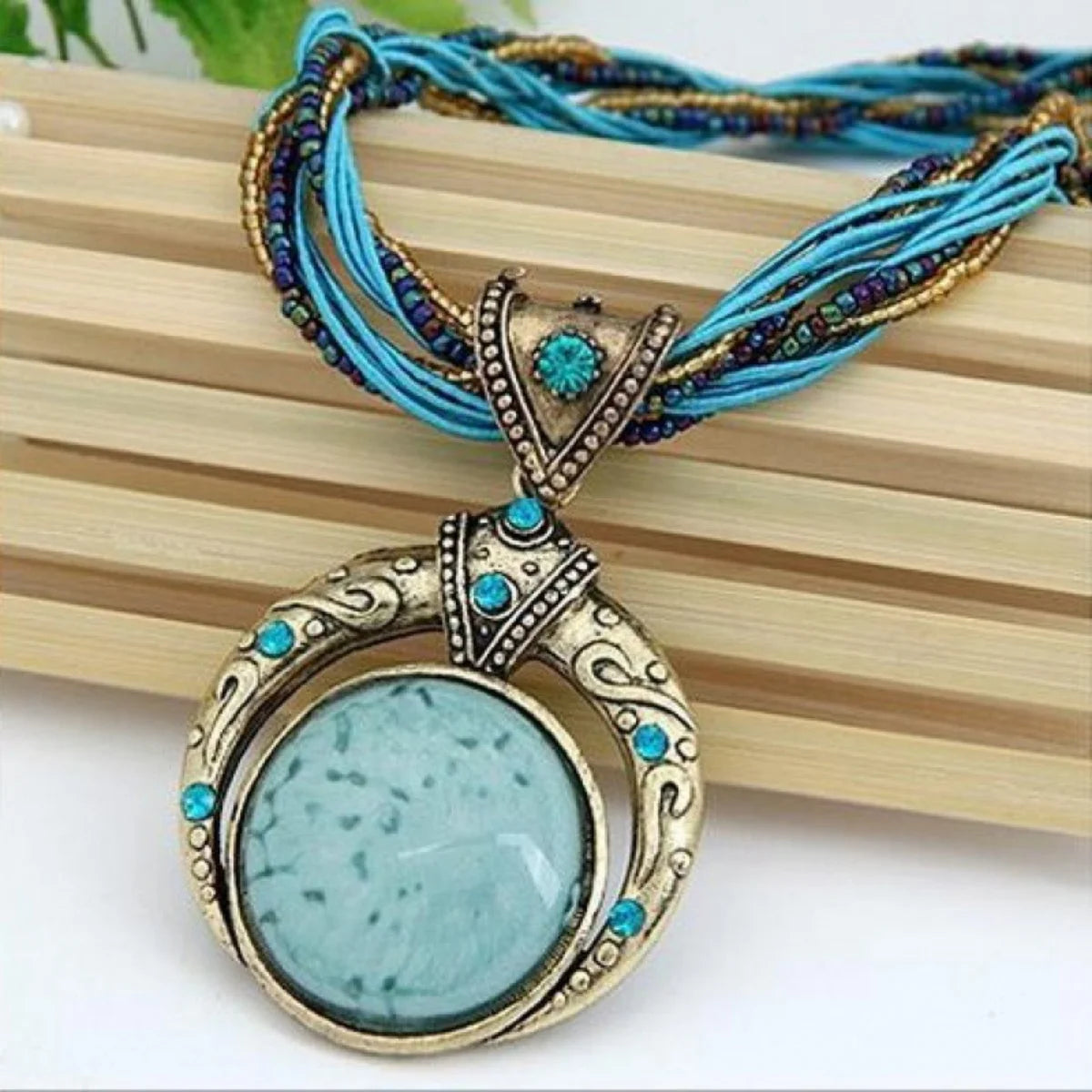 Vintage necklace with a turquoise pendant and blue cord on a wooden surface