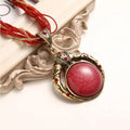 Vintage necklace with a red pendant on a decorative background