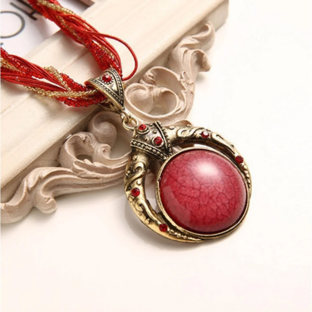 Vintage necklace with a red pendant on a decorative background