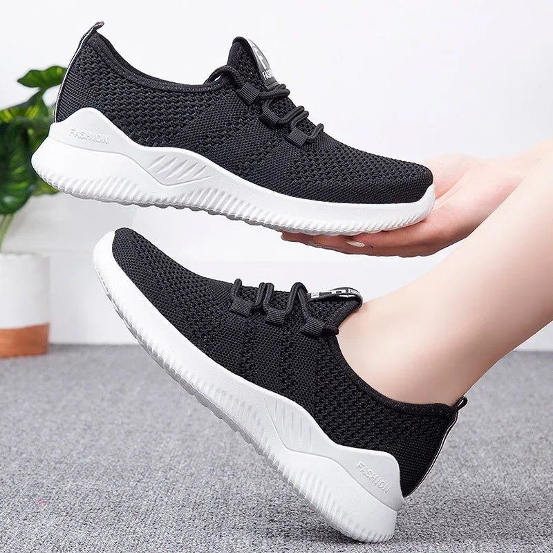 Black and white running shoes held by a model with a neutral background