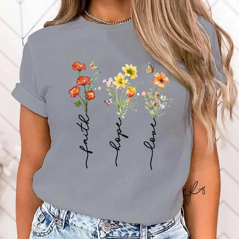 Gray t-shirt with floral design and text 'faith hope love' worn by a person.