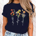 Navy blue t-shirt with floral design and 'faith hope love' text worn by a person.