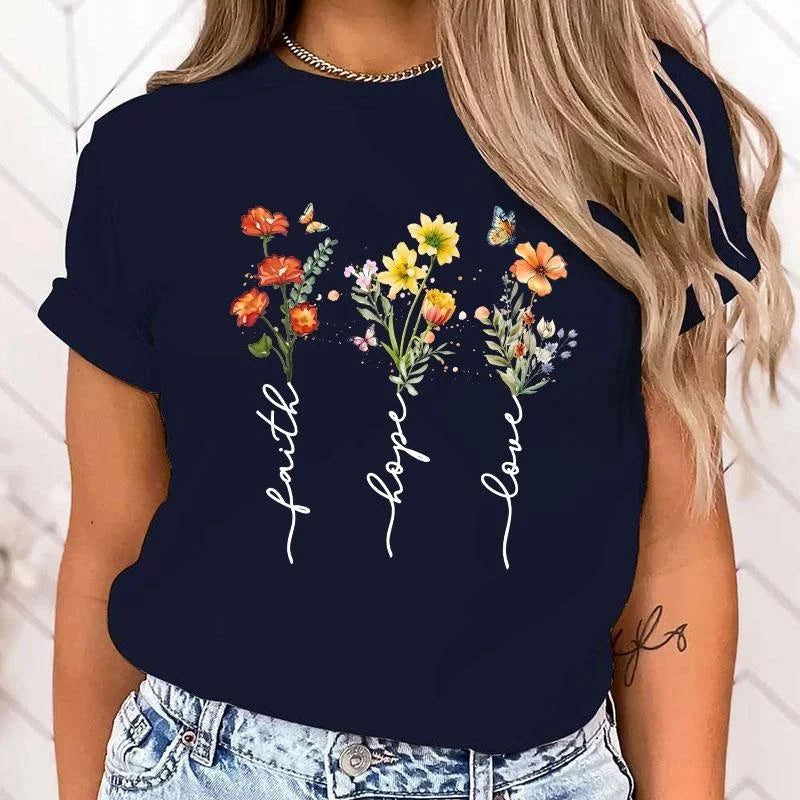 Navy blue t-shirt with floral design and 'faith hope love' text worn by a person.