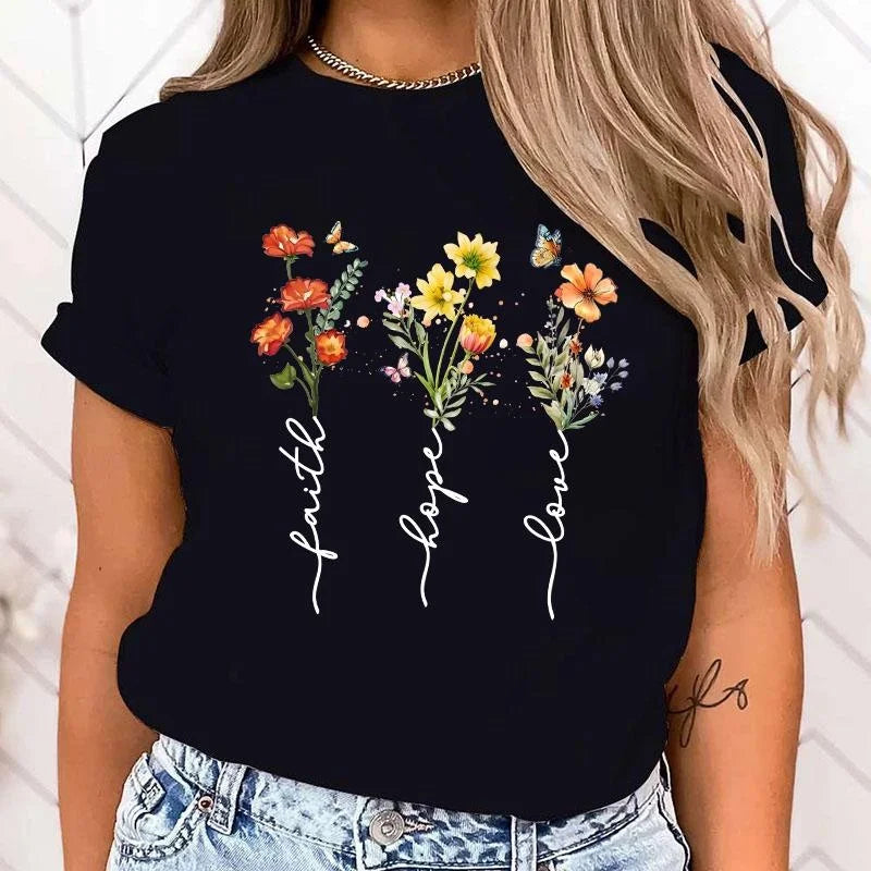Black t-shirt with floral design and 'faith hope love' text worn by a person.