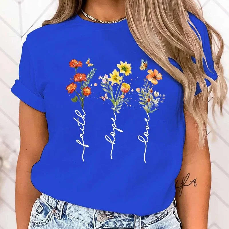 Person wearing a blue t-shirt with floral designs and 'faith hope love' text.