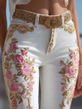 White pants with pink floral embroidery and a gold belt.