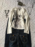 White blouse with lace details and dark jeans on a textured white background