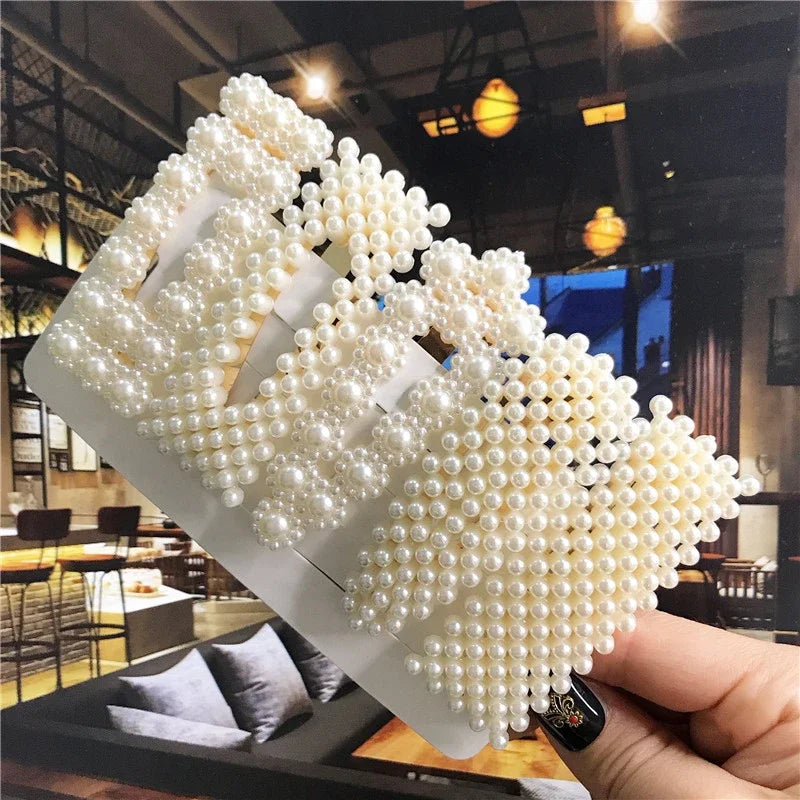 Hair clips with pearl-like beads held in a hand, indoor setting