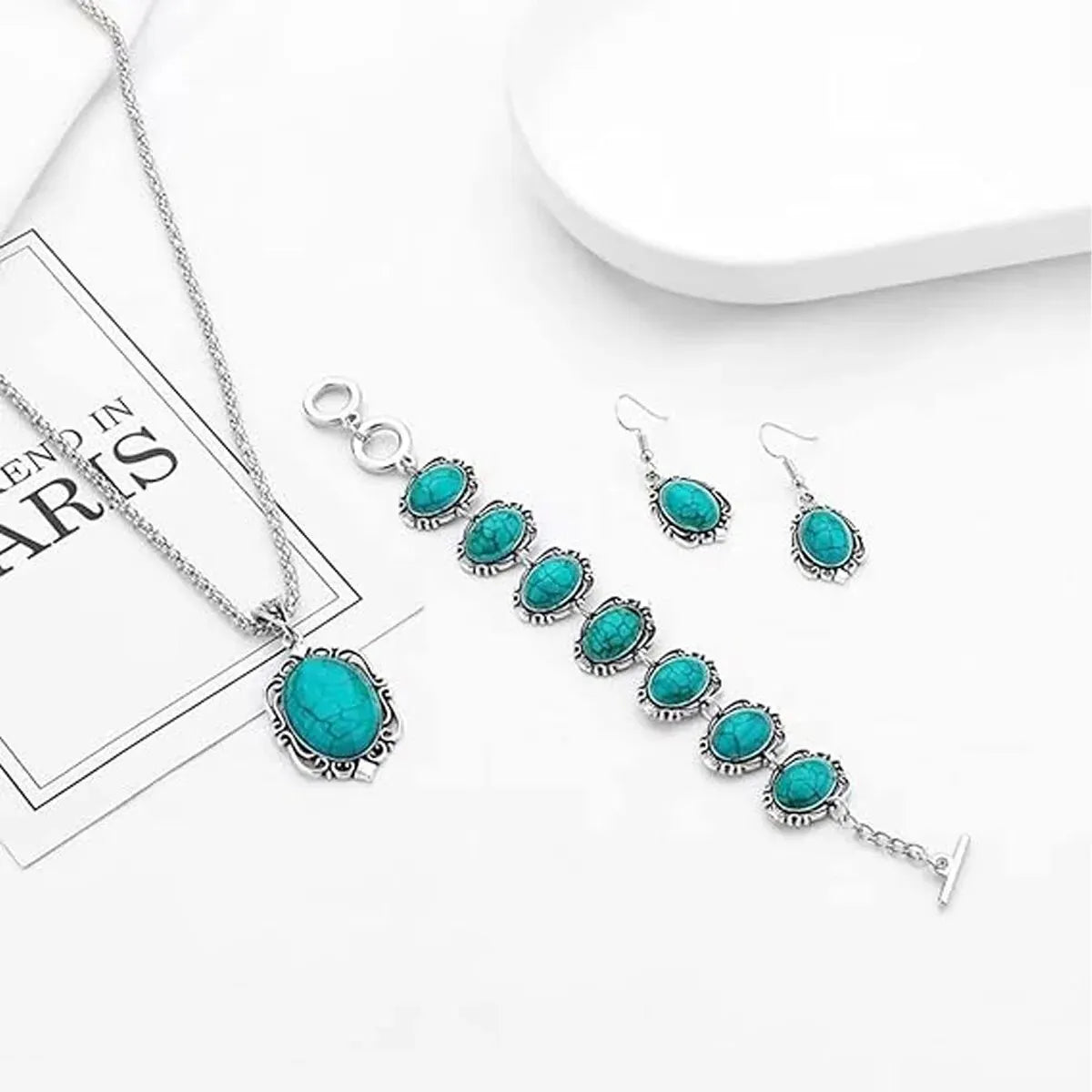 Turquoise jewelry set including necklace, bracelet, and earrings on a white surface.