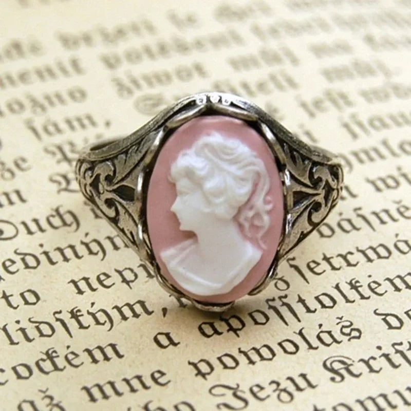 Vintage-style ring with a pink cameo on an old text background