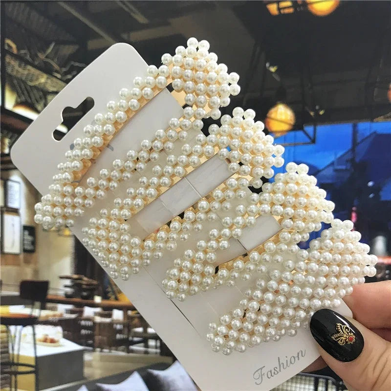Pearl-studded hair clips on a card held by a hand in an indoor setting.