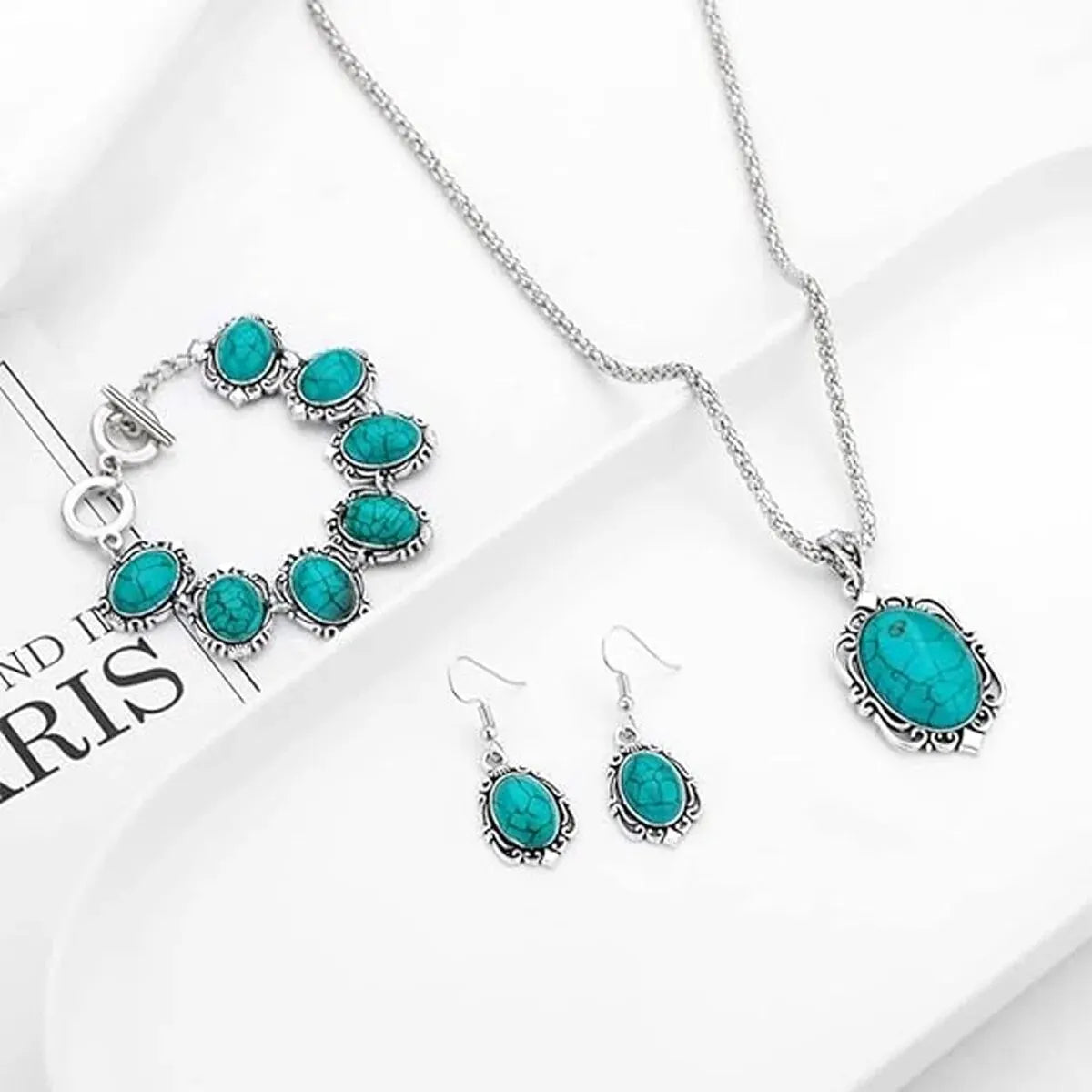 Turquoise gemstone jewelry set including necklace, bracelet, and earrings on a white background.
