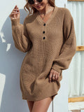 Woman wearing a brown knit dress with black buttons against a white wall.