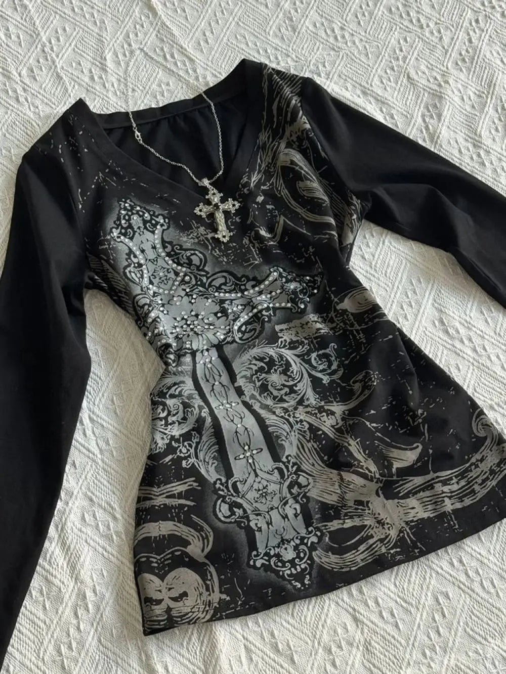 Black shirt with silver embroidery on a textured white surface