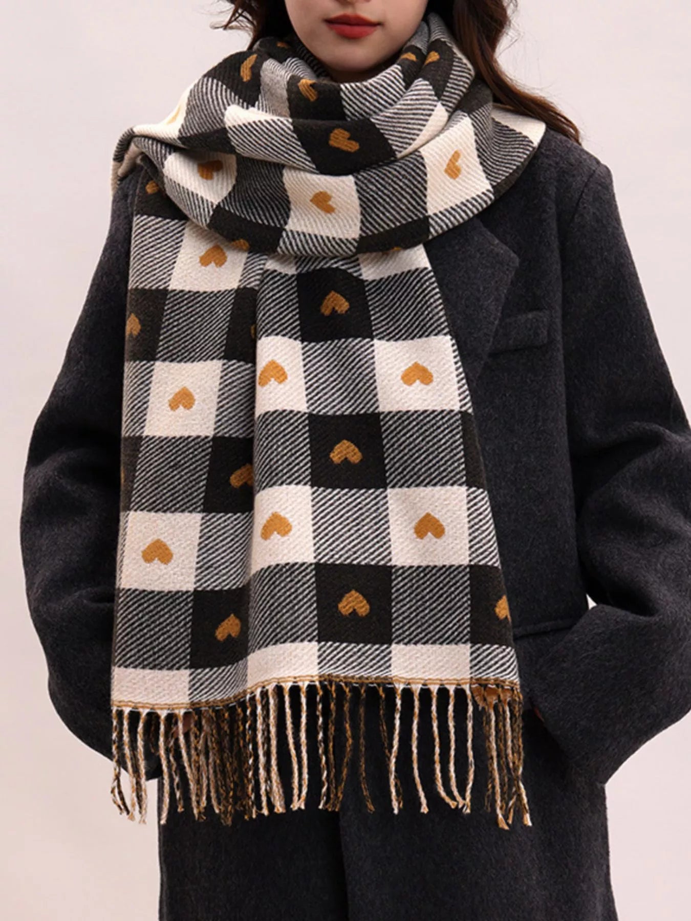 Model wearing a black and white checkered scarf with heart patterns on a plain background