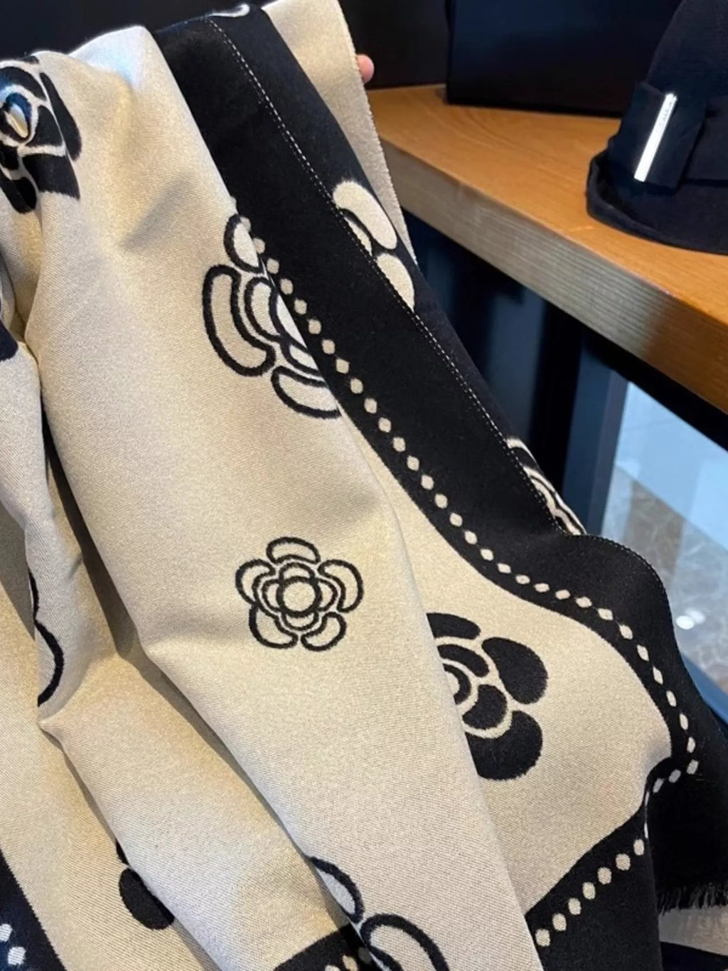 Beige fabric with black floral patterns on a wooden surface