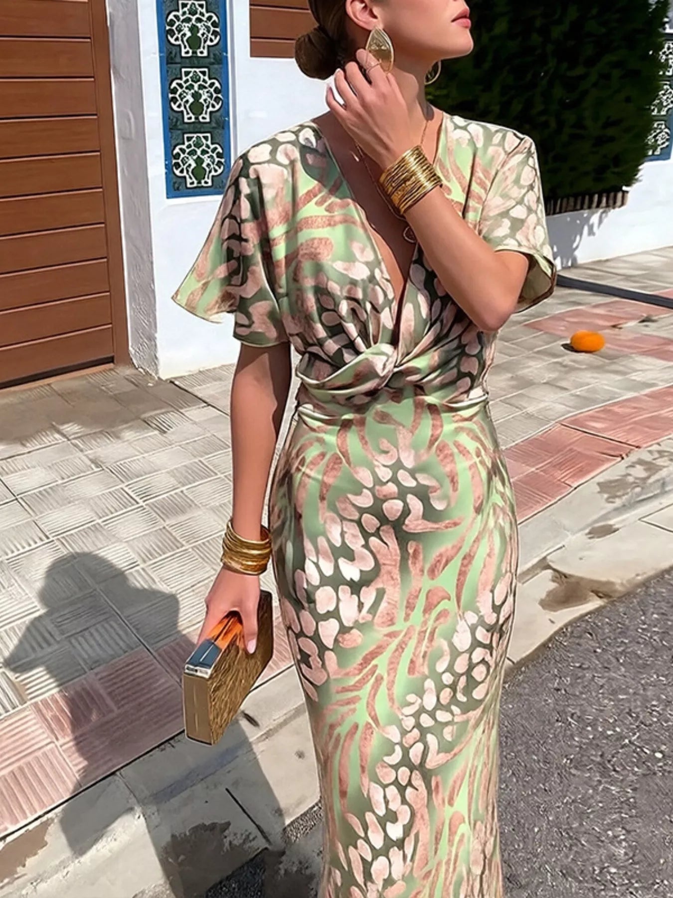 Woman in a patterned dress holding a clutch on a street.