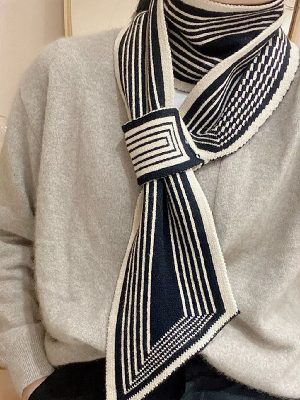 Model wearing a navy and white striped scarf on a light gray sweater.