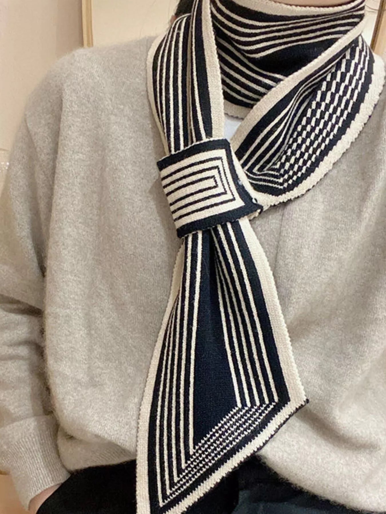 Model wearing a navy and white striped scarf on a light gray sweater.
