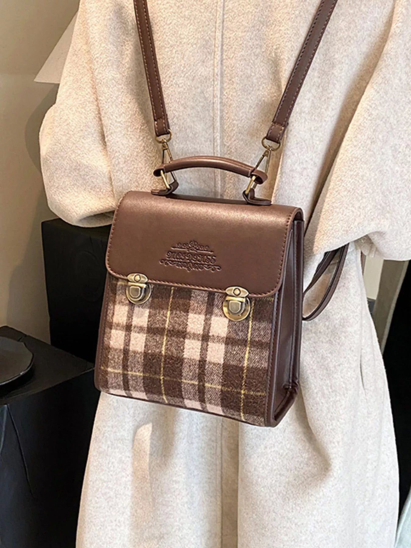 Brown plaid handbag with leather accents on a light gray coat