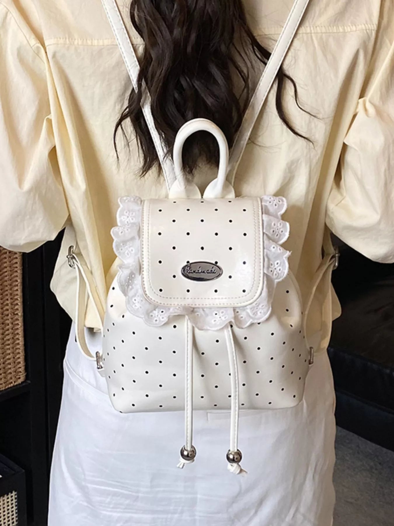 White polka dot backpack with lace details worn by a person