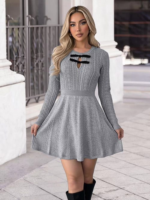 Woman wearing a gray knit dress with black accents in an urban setting.