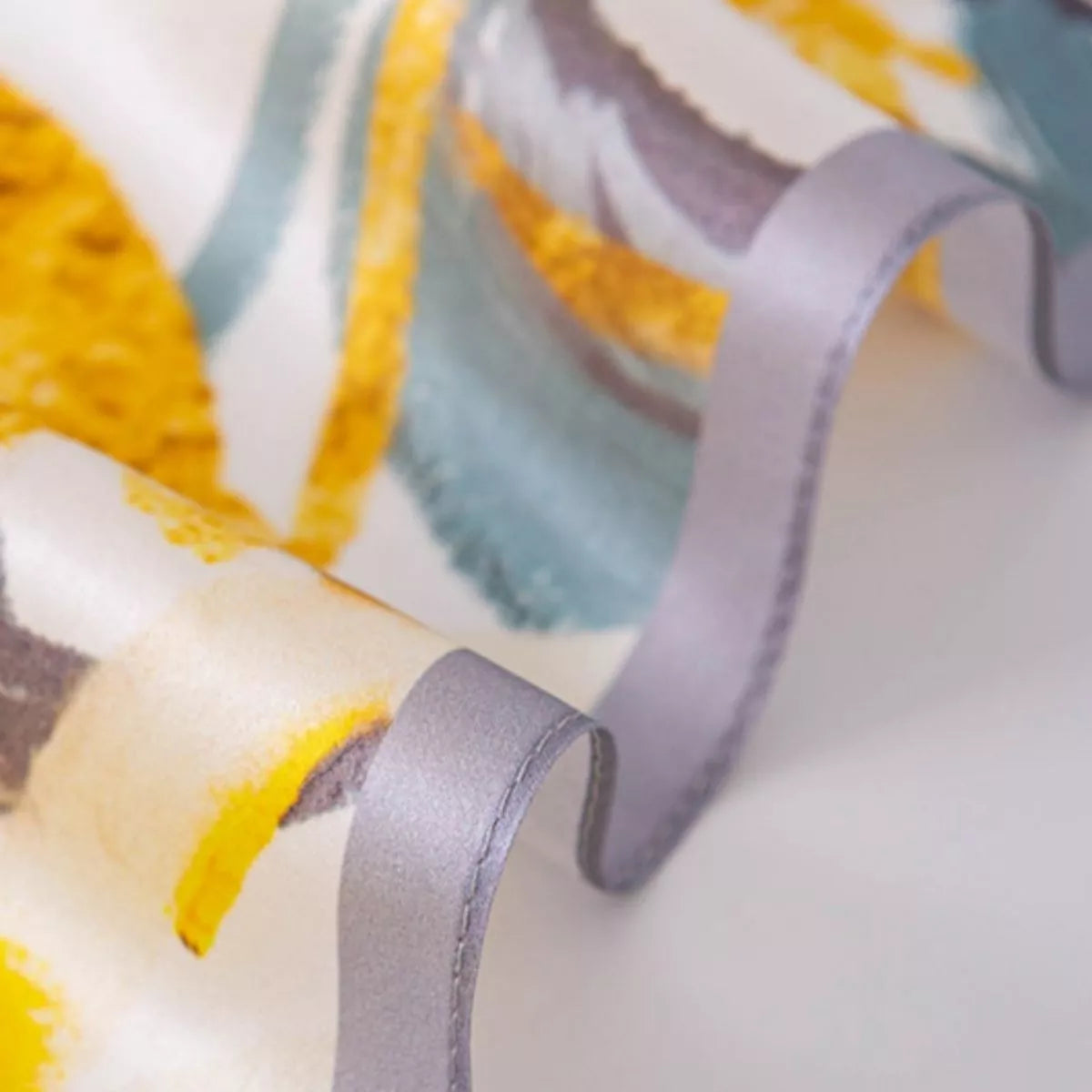 Close-up of a fabric with colorful patterns and a gray ribbon.