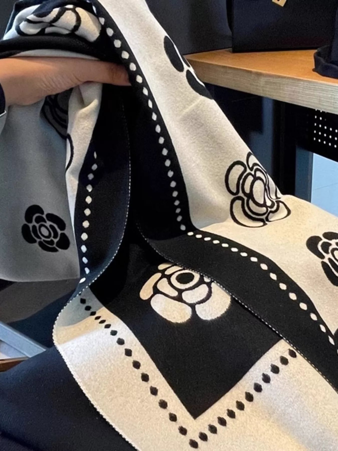 Black and white patterned fabric with floral designs held by a hand.
