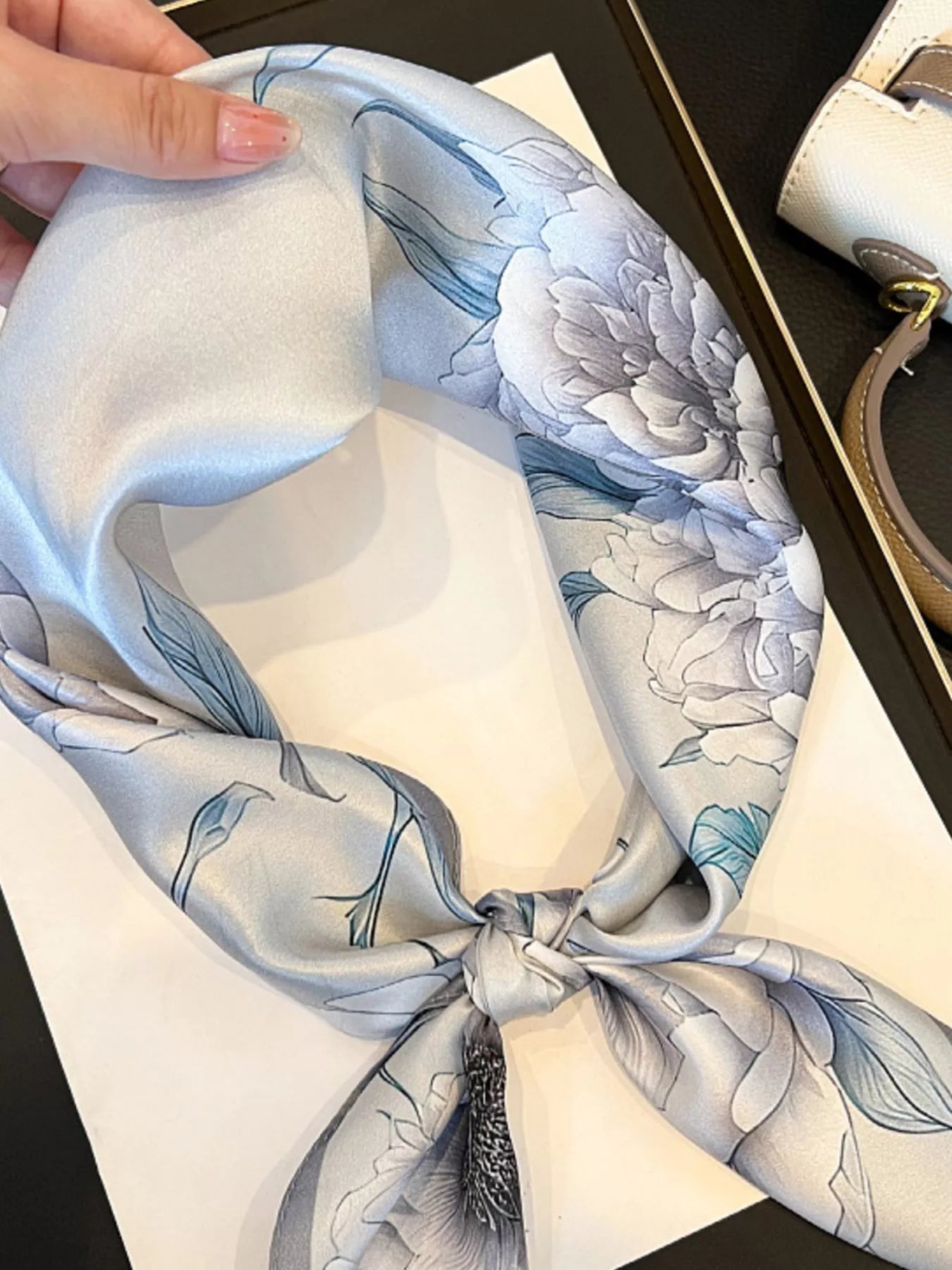 Floral patterned scarf with a decorative tassel on a plain background