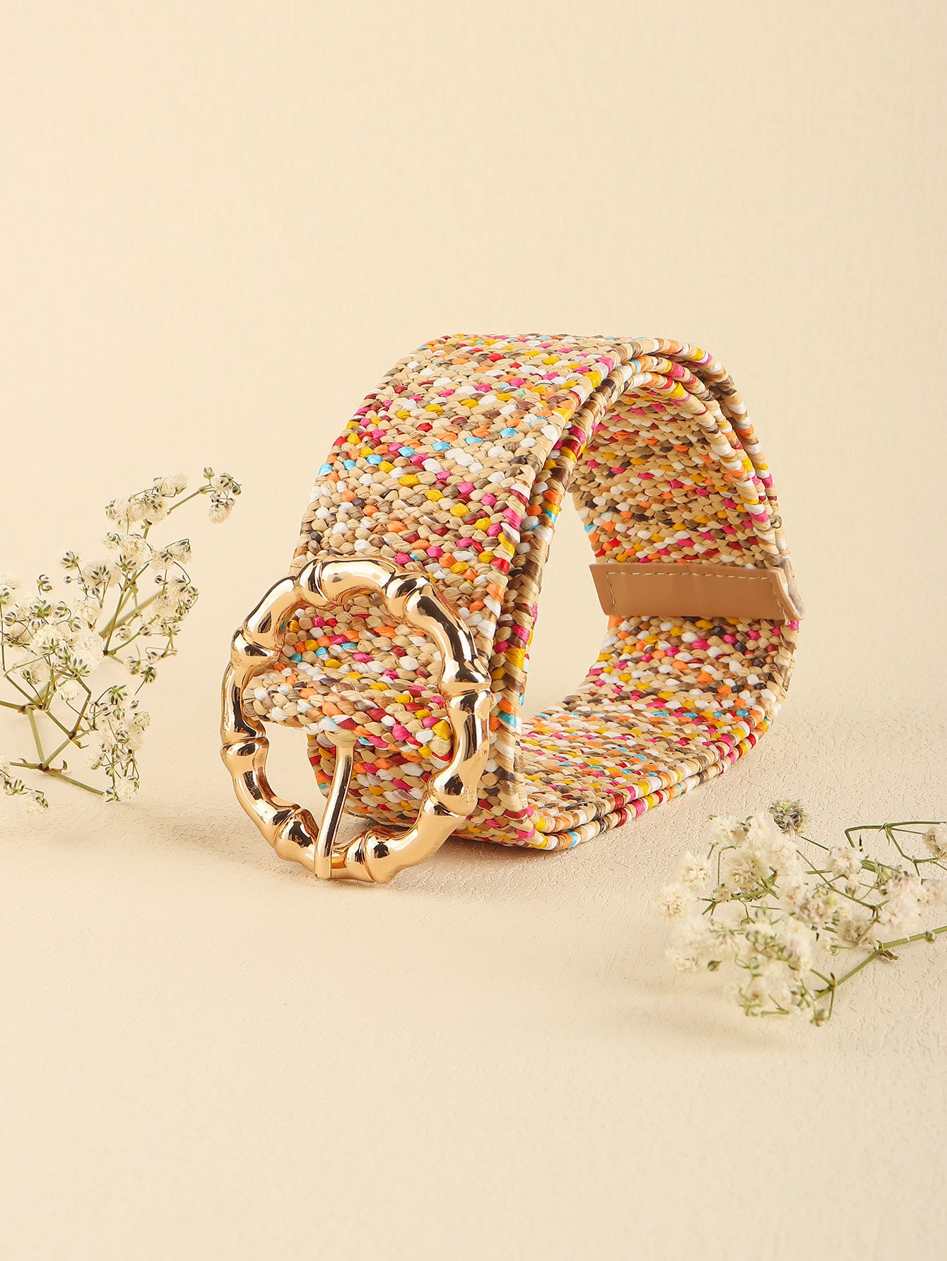 Multicolored woven belt with gold buckle on a beige background