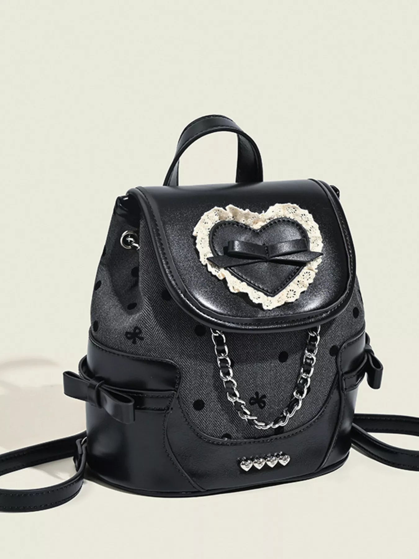 Black backpack with heart-shaped embellishment on a beige background