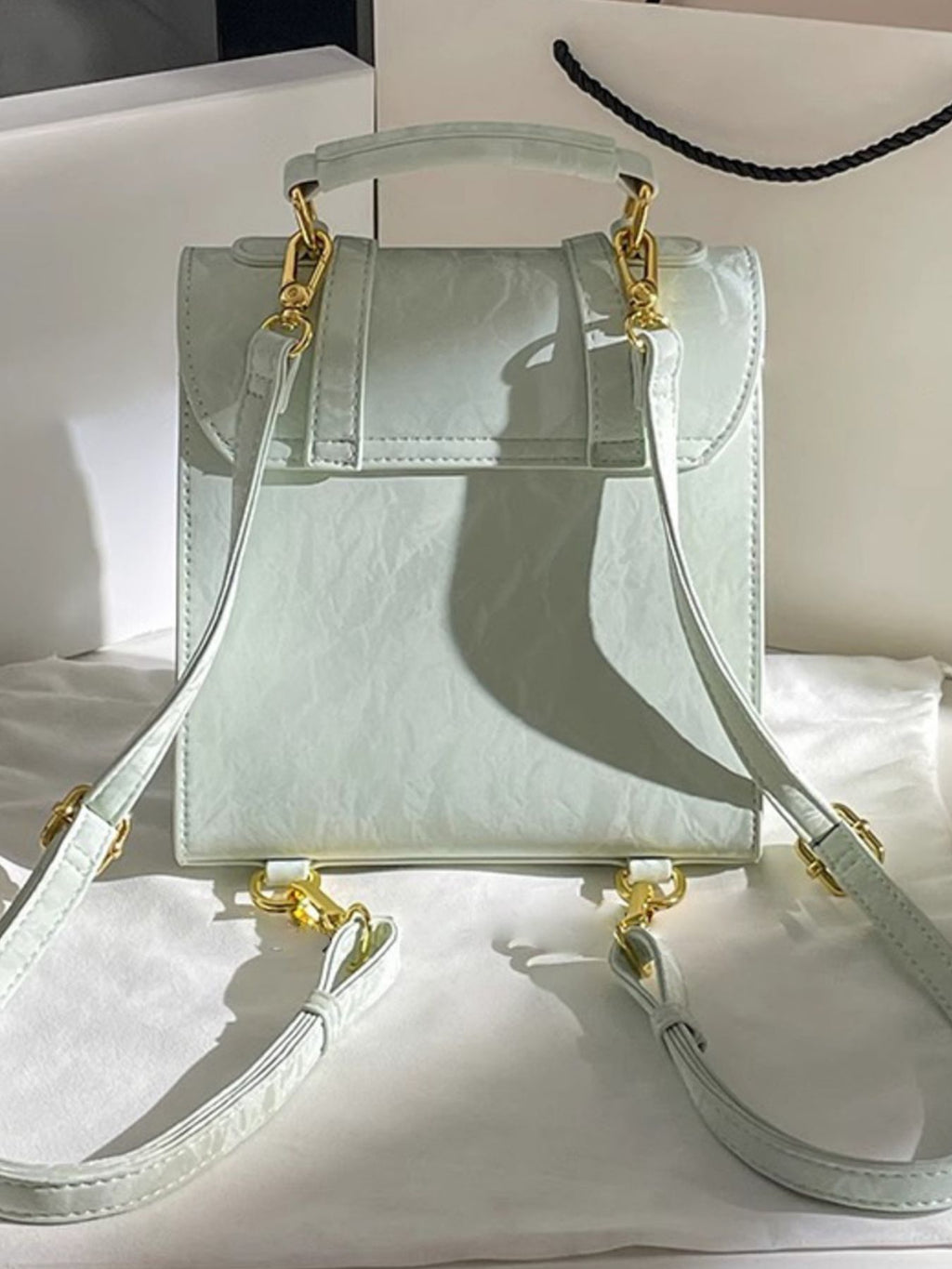 Light green handbag with gold accents on a white surface