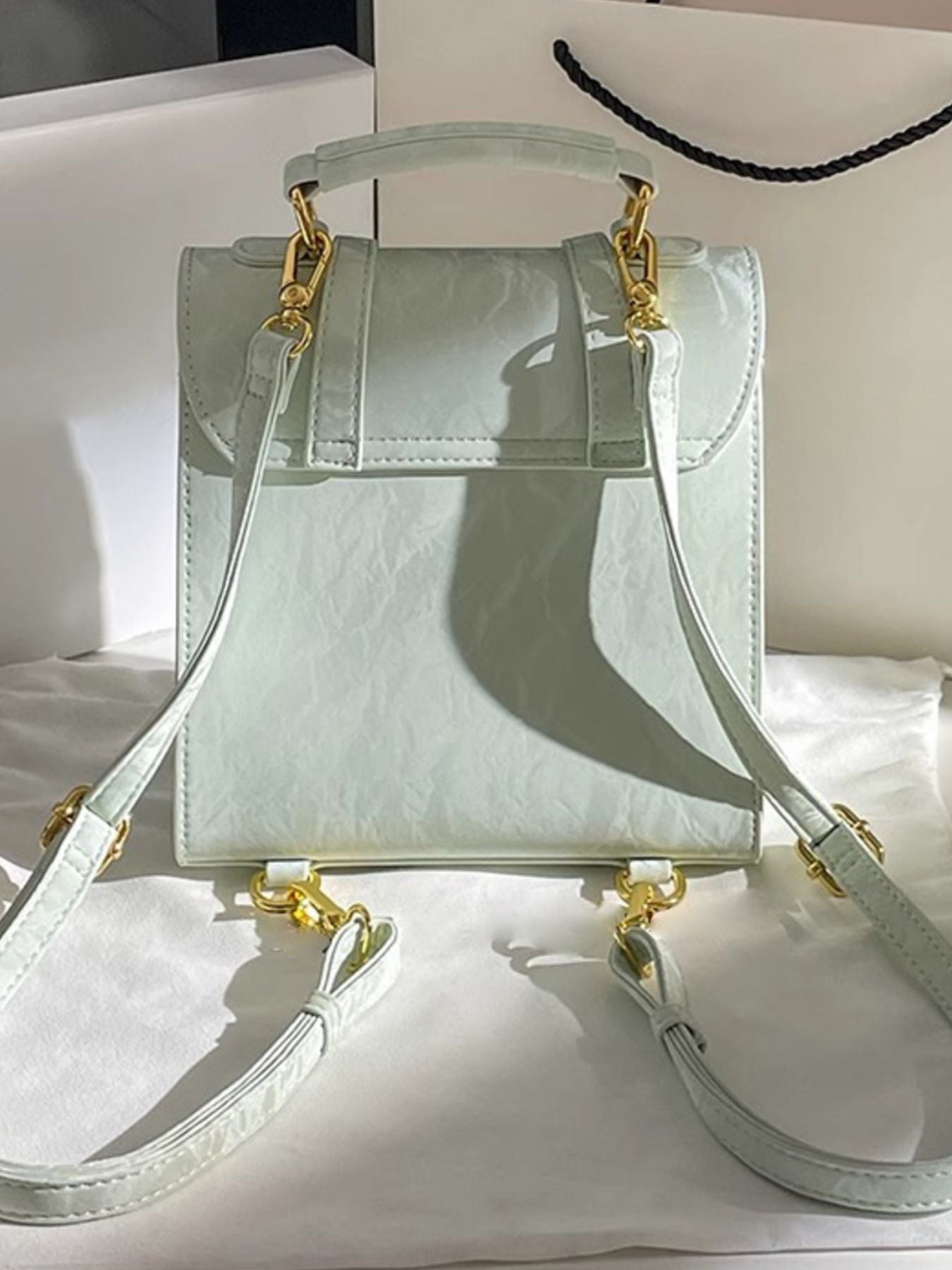 Light green handbag with gold accents on a white surface