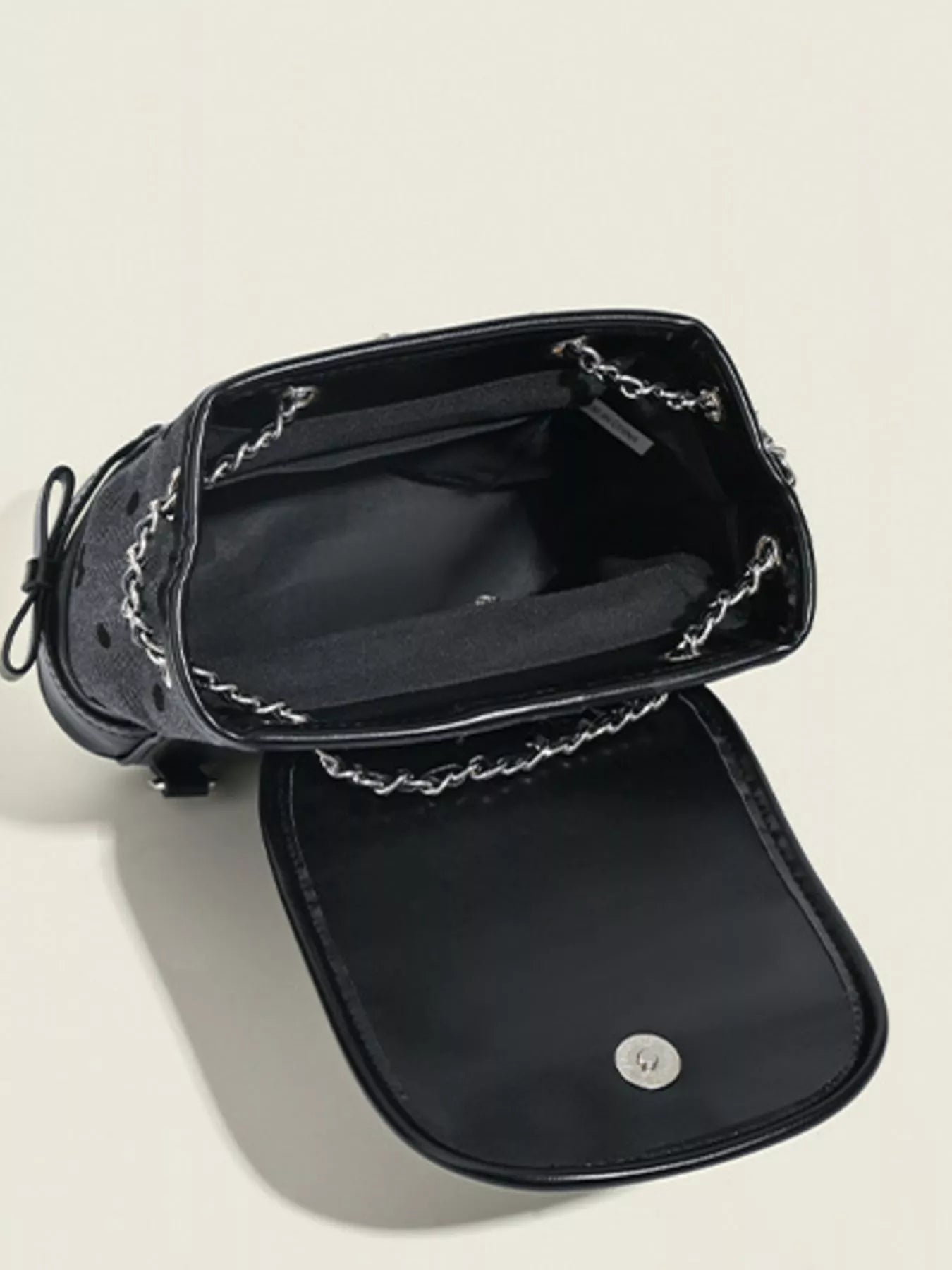 Black handbag with chain detail on a light gray background