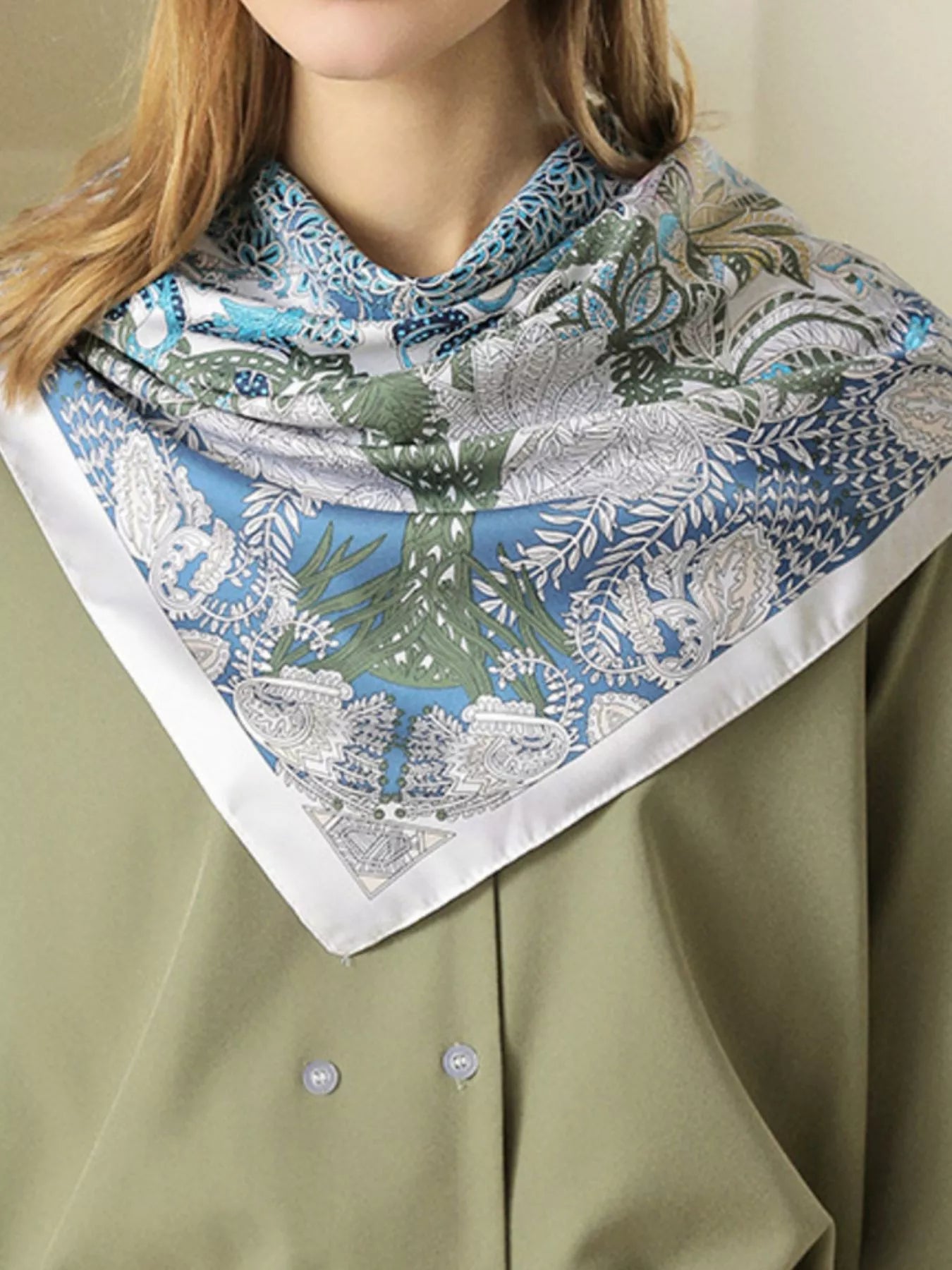 Model wearing a patterned scarf on a plain background