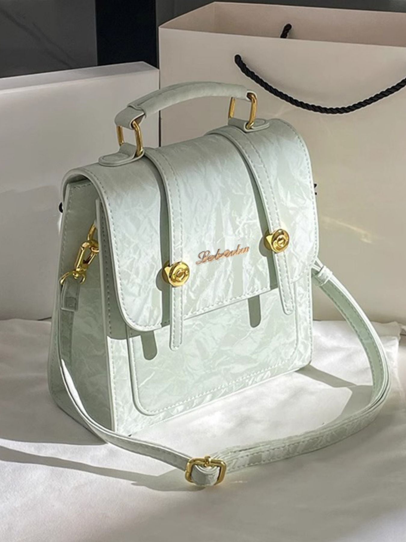 Light green handbag with gold accents on a white surface