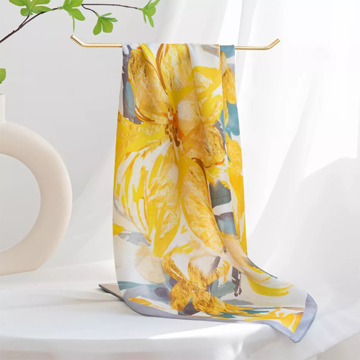 Yellow floral scarf draped over a white surface with a minimal background