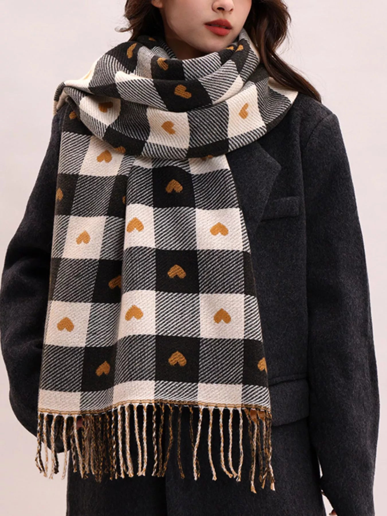 Model wearing a black and white checkered scarf with heart patterns on a plain background
