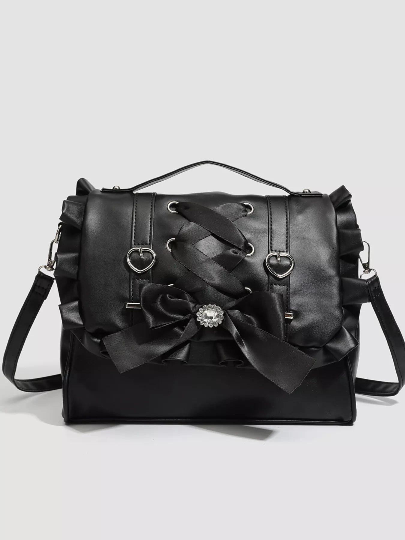 Black handbag with decorative bow and heart-shaped clasps on a light gray background